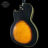 Guitar body with a black finish and orange-brown center on a black background, featuring 'Tone Shop' logo.