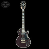 Electric guitar with a dark finish on a black background, featuring the Tone Shop logo.