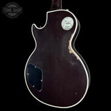Back view of a guitar with a visible brand logo on a black background