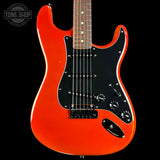 A classic electric guitar with a vibrant orange body, black pickguard, and maple fretboard, shown against a solid black background with a Tone Shop watermark in the top left corner.