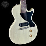 White electric guitar with a black pickguard on a black background, featuring 'Tone Shop' branding.