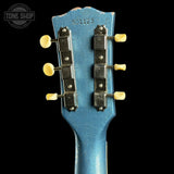 Close-up of a blue guitar headstock with tuning pegs on a black background, featuring 'Tone Shop' branding.