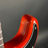Close-up of the lower bout corner of a glossy red electric guitar body with a black pickguard and visible wear marks on the glossy finish, set against a dark gray background.