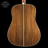 Back view of a wooden acoustic guitar with 'Tone Shop' logo in the corner.