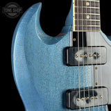 Close-up of a blue electric guitar with a black pickguard and visible brand logo.