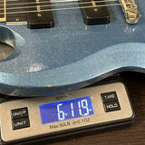 Blue electric guitar on a digital scale displaying weight