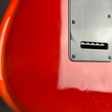 Close-up of a glossy red electric guitar body with a silver metal pickguard and visible wear marks and scratches.