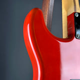 Close-up of a glossy red electric guitar body with part of the neck and headstock visible against a dark gray background.