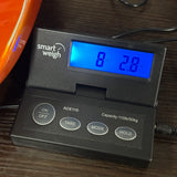 A smart weigh digital scale with a black plastic body, featuring a blue backlit LCD display showing '8 lbs 2.8 oz' and buttons labeled ON/OFF, TARE, MODE, and HOLD.