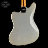 The back of a Fender electric guitar with a silver glitter finish, a natural maple neck, and a black Fender logo plate, shown against a solid black background.
