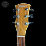Close-up of a Grech acoustic guitar headstock with six silver tuning pegs and six strings, set against a solid black background with a Tone Shop watermark in the upper left corner.