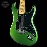 Green electric guitar with a black pickguard on a black background, featuring 'Tone Shop' logo.