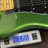 Green electric guitar being weighed on a digital scale