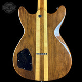 The back of a custom electric guitar made of rich brown wood with two vertical light maple wood stripes, shown against a solid black background.