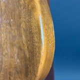 Close-up of a polished wooden object with a glossy finish and visible wood grain, set against a solid blue background.