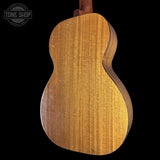 Back view of a wooden acoustic guitar on a black background with 'Tone Shop' logo.