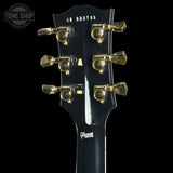 Guitar headstock with gold tuning pegs on a black background, featuring the Gibson logo.