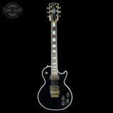 Black electric guitar with gold hardware on a black background, featuring the Gibson logo.