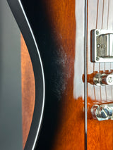 Close-up of a guitar's neck and headstock with visible wear.