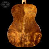 Close-up of a guitar's wooden back with a visible brand logo in the corner.
