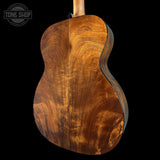 Wooden acoustic guitar body with 'Tone Shop' logo in the corner