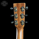 Close-up of a guitar headstock with tuning pegs on a black background, featuring the Tone Shop logo.
