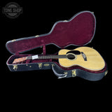 Acoustic guitar in an open case with 'Tone Shop' branding.