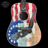 Acoustic guitar with a colorful design featuring an eagle, stars, and a building on a black background.