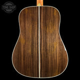 Back view of a wooden acoustic guitar with 'Tone Shop' logo.