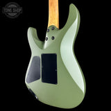 The back of an electric guitar with a sage green body, black pickups, and a natural wood neck, shown against a solid black background.