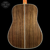 Close-up of a wooden acoustic guitar back with 'Tone Shop' logo.