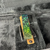 A custom leather strap key holder with a green and yellow lightning-bolt pattern, shown inside a black plush case next to a metal hex key tool.