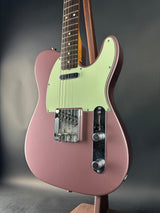 Pink electric guitar on a reflective gray surface