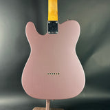 Pink electric guitar on a stand with a dark gray background