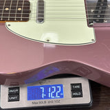 Pink electric guitar on a digital scale displaying weight