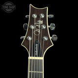 Close-up of the headstock of a guitar, showing the brand name 'Followbody' and model 'SE', with six silver tuning pegs and a dark brown wood finish against a black background.