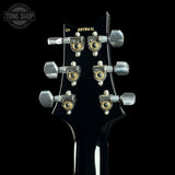 Close-up of a guitar's tuning pegs with 'Tone Shop' branding in the corner.