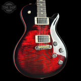 Red electric guitar with a black background, featuring the Tone Shop logo.