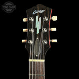 Close-up of a vintage Collings acoustic guitar headstock, showing the dark wood finish, six tuning pegs, strings, and a light-colored logo on a black background.