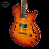 A double-cutaway electric guitar with a vibrant sunburst finish, featuring a bright orange and red center with dark brown edges. The guitar has black hardware, chrome pickups, and a white binding on a solid black background.