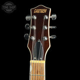 Close-up of the headstock of a Gretsch electric guitar against a black background, showing the Gretsch logo, six tuning pegs, and part of the fretboard.