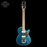 A blue electric guitar with a maple neck, chrome hardware, and a red-and-black pickguard, shown against a solid black background with a Tone Shop watermark in the top-left corner.