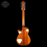 A classic electric guitar shown from the back, featuring a glossy warm brown wood finish, dual circular chrome tuning peg covers, and a cream-colored tailpiece, set against a solid black background with a Tone Shop watermark in the top left corner.