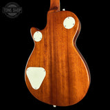 The back of a classic electric guitar with a glossy reddish-brown wood finish, featuring cream-colored pickpockets and a matching backplate, shown against a solid black background.