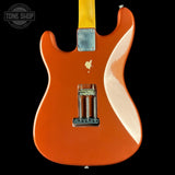 Orange electric guitar with a white pickguard on a black background, featuring the Tone Shop logo.