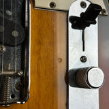 Close-up detail of an electric guitar body showing the wood grain finish, metal hardware, strings, and control knobs.