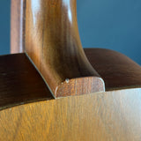 Close-up detail of a wooden acoustic guitar body showing the sound hole surround and wood grain against a dark blue background.