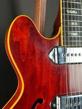 Close-up of a red electric guitar with a focus on the body and neck.