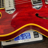 Red electric guitar on a digital scale displaying weight