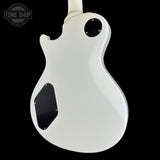 The rear view of a white electric guitar body with black pickguard and gold-tone hardware, shown against a solid black background with a Tone Shop watermark in the top left corner.